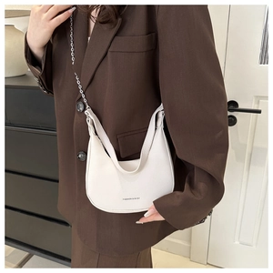 Close-up of white crescent bag featuring pebble grain texture and metal chain detail