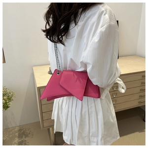 Détail d'un sac en cuir rose asymétrique géométrique avec chaîne argentée