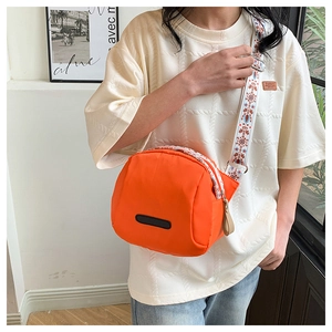 Detail showing the orange nylon shell bag with bohemian jacquard wide shoulder strap