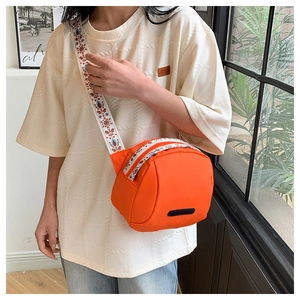 Detail of bright orange nylon crossbody bag with ethnic floral embroidered wide strap