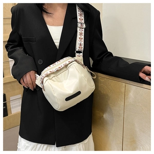 Detail of cream nylon shell bag with colorful ethnic patterned wide shoulder strap