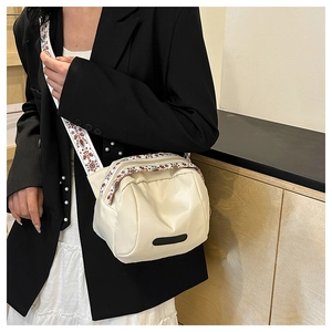 Detail of off-white shell bag with wide ethnic pattern strap and long black accents