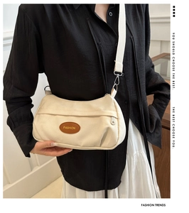 Detail of cream canvas bag with brown leather FASHION patch and wide strap on model