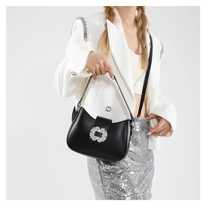 Elegant black crescent shoulder bag with crystal buckle shown on a model in a white blazer