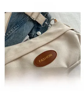 Detailed close-up of beige canvas bag with brown leather fashion logo on denim fabric