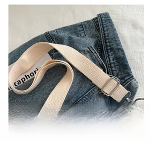 Close-up of adjustable cream canvas strap with silver metal hooks for shoulder bag