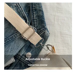 Detail of adjustable silver metal buckle on cream canvas shoulder strap with denim accents