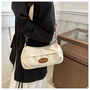 Detail of vintage canvas crossbody bag featuring brown leather patch and gold fashion text