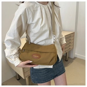 Detail shot of khaki canvas crossbody bag with leather logo and front zipper pocket