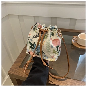 Detail of floral woven tapestry fabric and brown leather drawstring on bucket bag