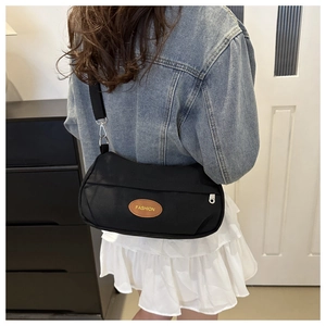 Dettaglio di una borsa vintage nera in tela con toppa in pelle marrone e tracolla sportiva