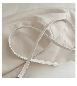 Close-up of the elegant cream white leather strap with fine stitching on a square bag