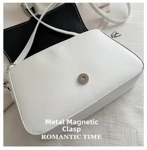 Detail shot of the white crossbody bag featuring a magnetic buckle and leather texture