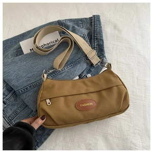 Dettaglio borsa a tracolla in tela kaki con ampia tracolla e etichetta in pelle vintage
