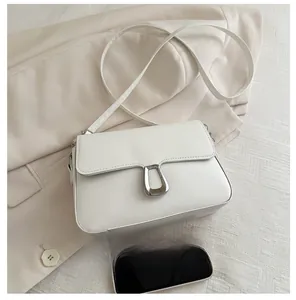 Detailed size comparison of white leather crossbody bag with a smartphone on beige blazer