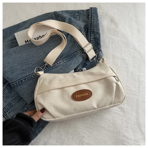 Dettaglio borsa a tracolla in tela beige con toppa in pelle marrone e tracolla larga