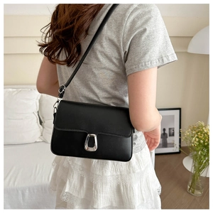 Black rectangular flap bag with silver metal clasp worn over the shoulder by model