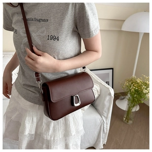 Detail of vintage dark brown square bag with silver metal buckle and adjustable strap