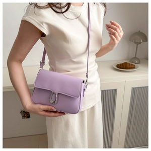 Close-up of a stylish lavender crossbody bag with silver U-shaped metal buckle on a model