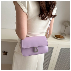 Lavender purple leather crossbody bag with silver U-shaped buckle in a minimalist home setting