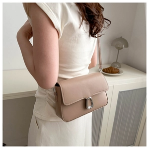 Minimalist light brown rectangular shoulder bag with silver buckle worn by a model