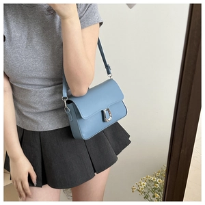 Detail of blue square shoulder bag with silver horseshoe buckle and adjustable strap