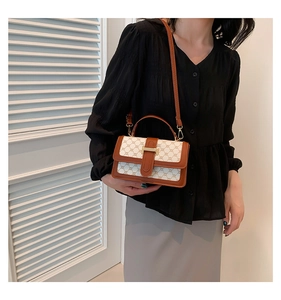 Detail of vintage crossbody bag featuring beige chain print and gold H-buckle on a model