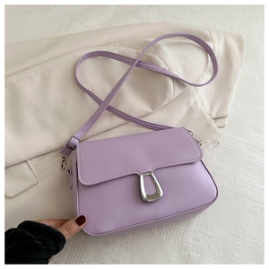 Detail of lavender PU leather crossbody bag with silver trapezoid clasp on beige blazer