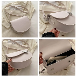 Detail view of the cream semi-circular crossbody saddle bag with interior storage space