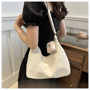 Détail d'un sac hobo beige en cuir souple avec un pendentif ours en peluche mignon