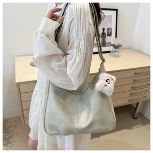 Sac hobo vert clair en daim avec pendentif chiot peluche sur robe d'été blanche
