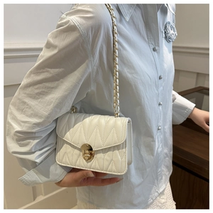 Détail d'un sac bandoulière blanc en similicuir matelassé avec fermoir doré et chaîne