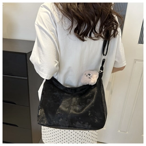 Détail du sac cabas en suédine noire avec bandoulière réglable et breloque panda doux