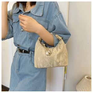 Detail of a cream pleated hobo bag with drawstring beads and textured nylon fabric