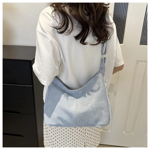 Détail du sac hobo bleu clair montrant la texture suédine et la large bandoulière souple