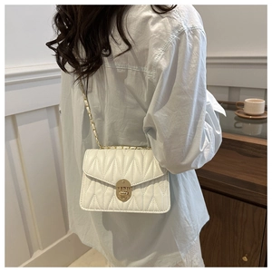 Close-up of a white quilted crossbody bag with gold chain strap and metal swivel lock