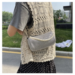 Close-up of sparkling rhinestone cylinder bag with pearl handle and metal chain