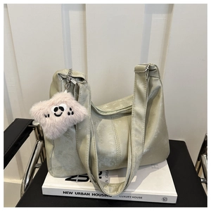 Détail du sac cabas en daim vert clair avec un charm monstre peluche sur des livres