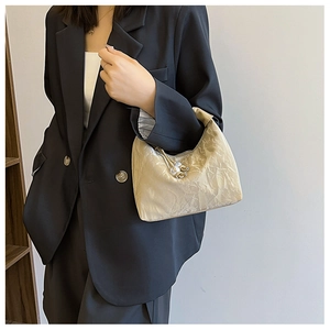 Detail of champagne gold dumpling bag with pleated metallic texture and beaded drawstring
