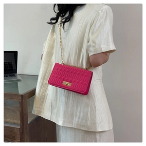 Détail du sac bandoulière matelassé rouge rose avec chaîne dorée et fermoir pivotant