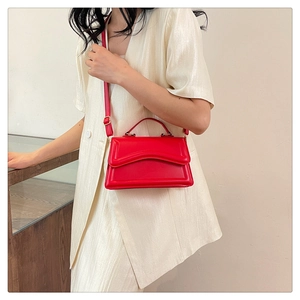 Detail view of the vibrant red glossy finish and elegant wave-shaped flap with gold buckle