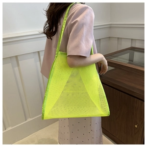 Dettaglio della borsa tote in rete verde neon con manici intrecciati sulla spalla