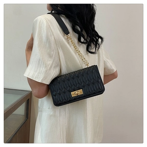 Sac bandoulière matelassé noir classique avec chaîne dorée porté par un mannequin