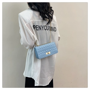 Détail du sac matelassé bleu clair avec coutures verticales et chaîne dorée