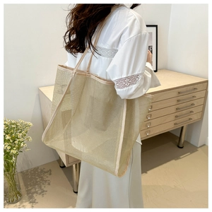 Détail d'un grand sac fourre-tout en résille beige montrant la texture ajourée et respirante