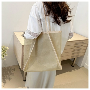 Dettaglio della borsa tote in rete beige con tessuto traslucido e tracolla larga morbida