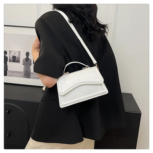 Detailed side view of white structured handbag with embossed curves and leather strap