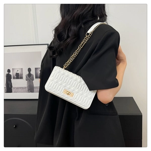 Détail du sac à bandoulière matelassé blanc avec chaîne dorée et fermoir pivotant