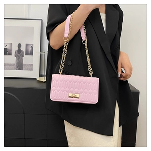Détail d'un sac à bandoulière rose matelassé avec chaîne dorée et fermoir tournant