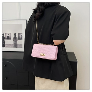 Sac bandoulière rose matelassé avec chaîne dorée et fermoir pivotant sur modèle